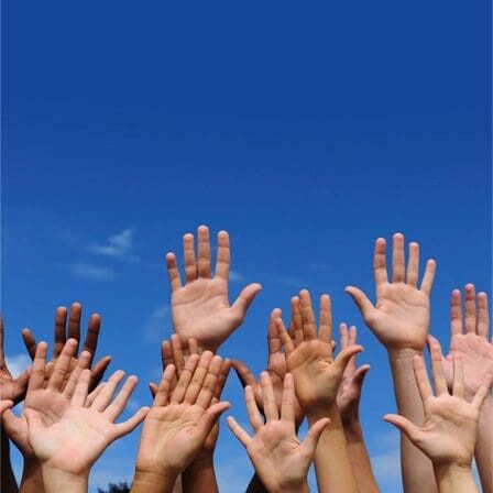 Multiple hands reaching up under a clear blue sky.